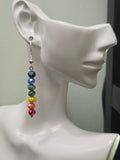 Rainbow glass bead drop earring displayed on white mannequin ear, showing full rainbow gradient from navy to magenta