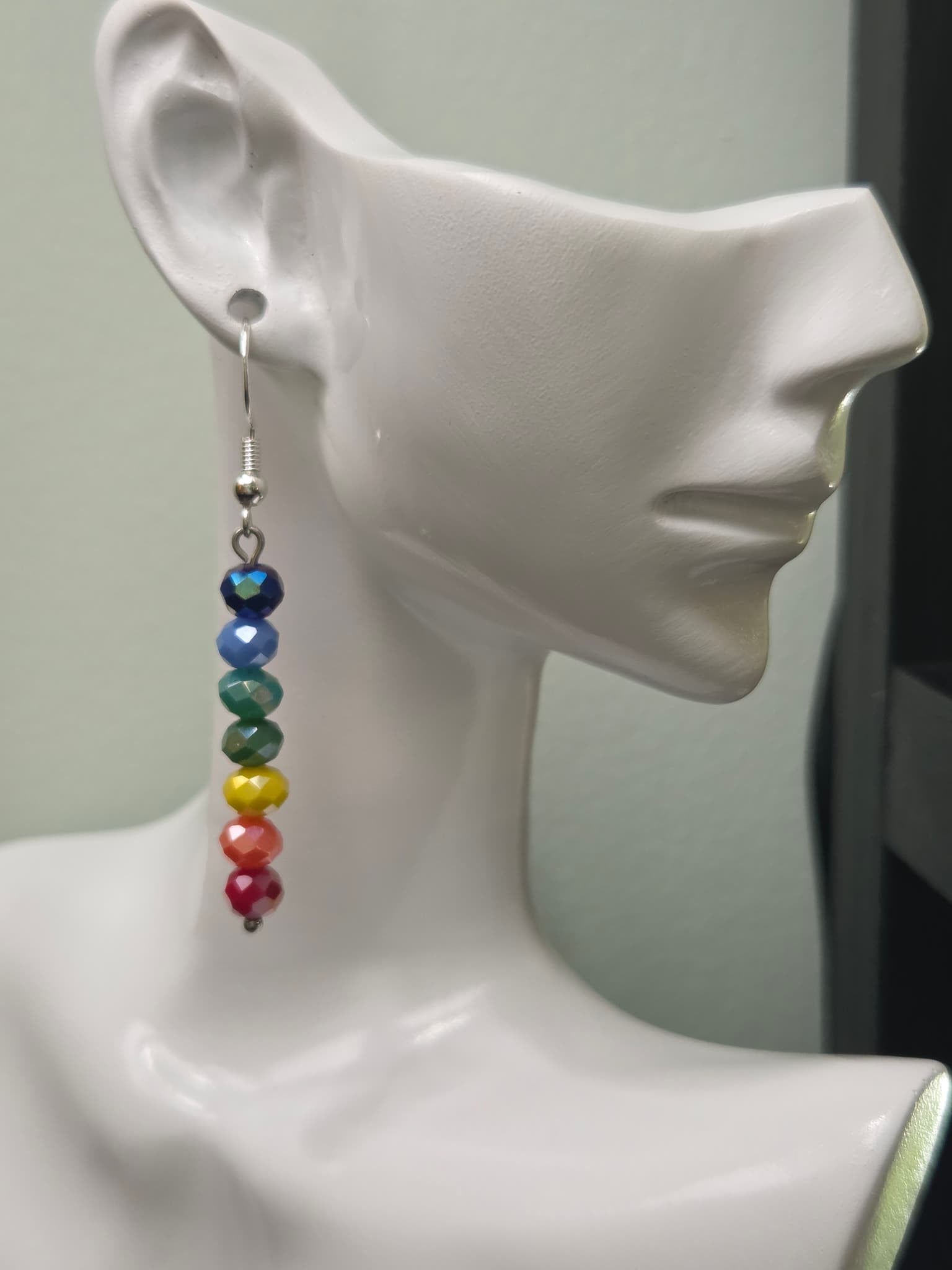 Rainbow glass bead drop earring displayed on white mannequin ear, showing full rainbow gradient from navy to magenta