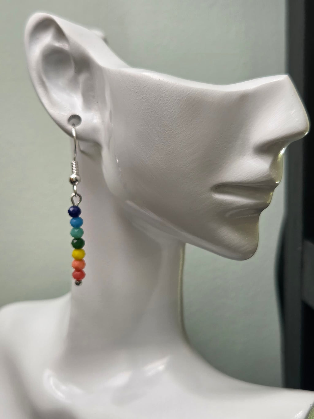 Rainbow glass bead drop earring displayed on white mannequin ear, showing full rainbow gradient from navy to magenta