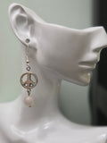 Silver peace sign and pale pink rose quartz bead drop earring worn on white mannequin ear, showing full length and movement