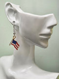 Handmade waving American flag earring on a white mannequin ear, showcasing red and white wavy enamel stripes with a navy blue star field in a gold-tone frame