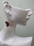 Handmade American flag butterfly earring on a white mannequin ear, featuring a navy blue enamel wing with white stars and a bold red and white striped enamel wing in a gold-tone frame