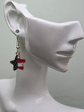 Handmade American flag diagonal star earring on a white mannequin ear, featuring a star-shaped charm with navy blue enamel and white stars on the upper half and bold red and white diagonal stripes on the lower half in a gold-tone frame