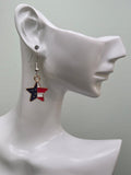 Handmade petite American flag split star earring on a white mannequin ear, featuring a star-shaped charm with navy blue enamel and white stars on the upper left and vivid red and white diagonal stripes on the lower right in a gold-tone frame