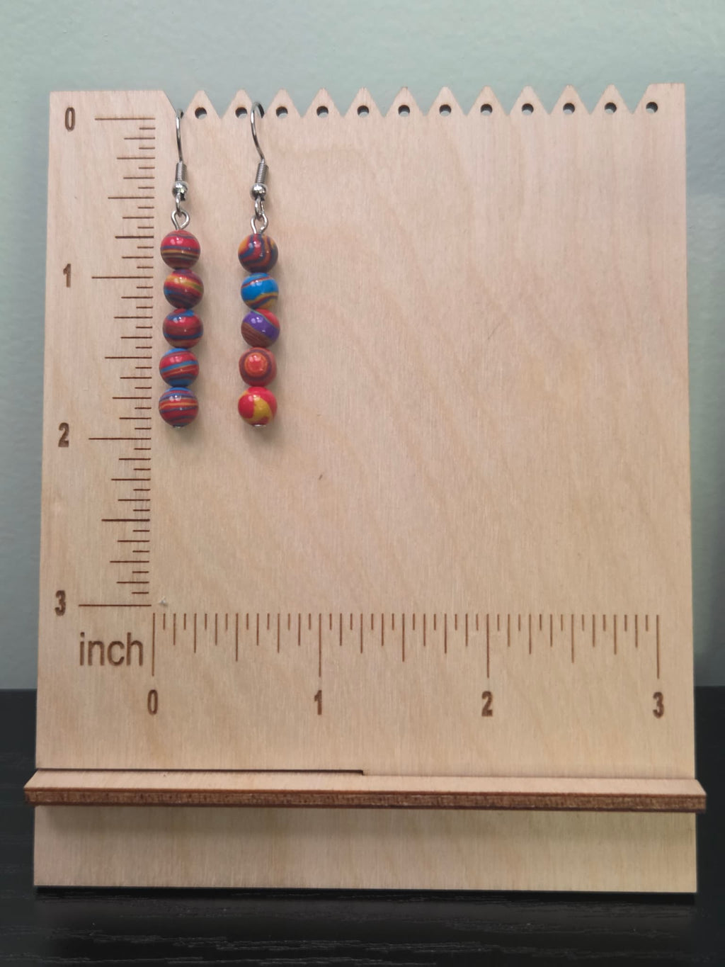 Rainbow swirl mystery stone stacked drop earrings shown on a ruler display — approximately 1.75 inches long — two pairs laid flat showing colorful marbled bead detail
