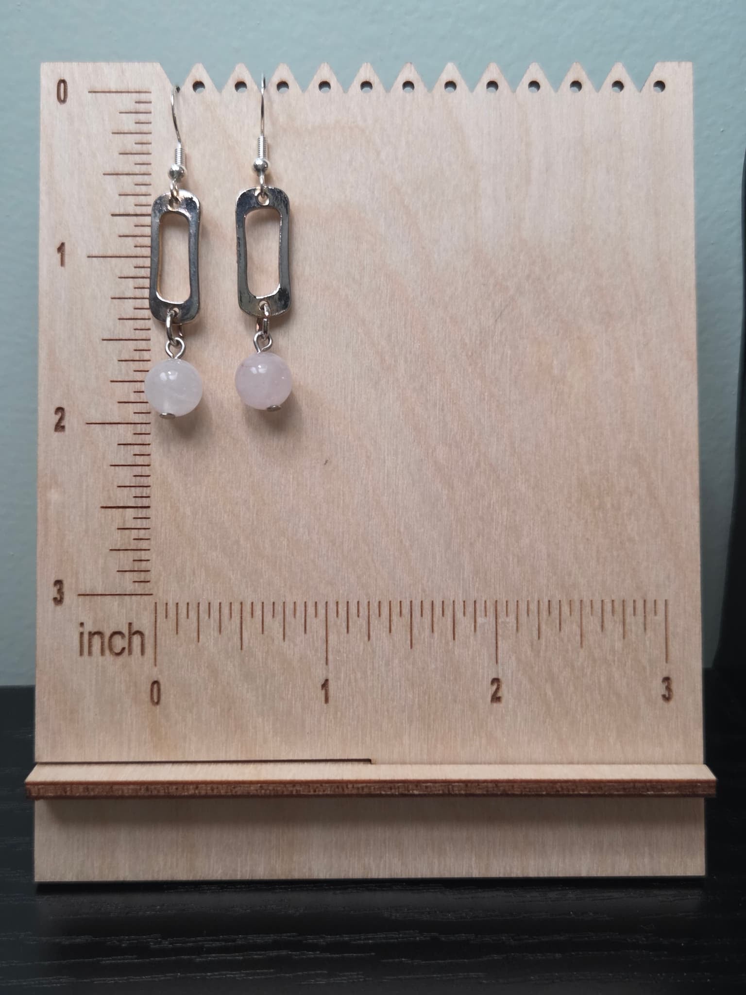 Rose quartz drop earrings with reclaimed silver-tone rectangular link connector, displayed on a wooden earring stand with ruler showing approximately 2 inch length