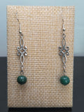 Close-up of silver-tone scrollwork drop earrings with genuine malachite beads