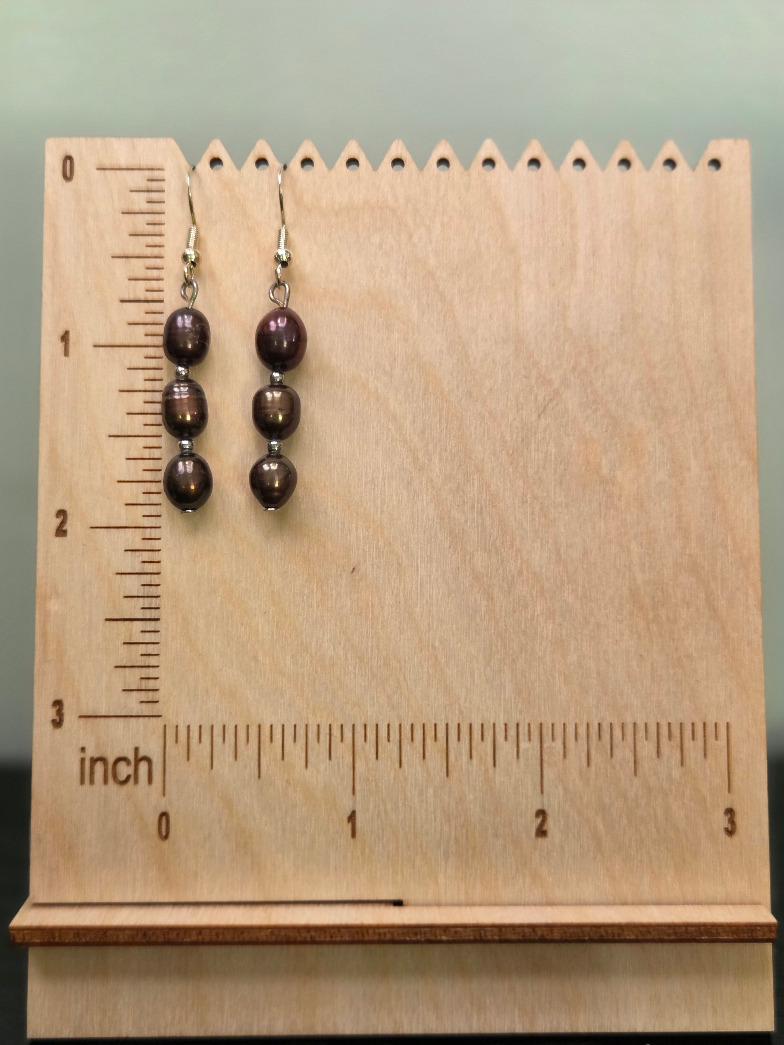 Three genuine dyed freshwater pearl beads stacked with silver-tone spacers, displayed on a wooden earring stand with ruler showing approximately 1.75 inch length