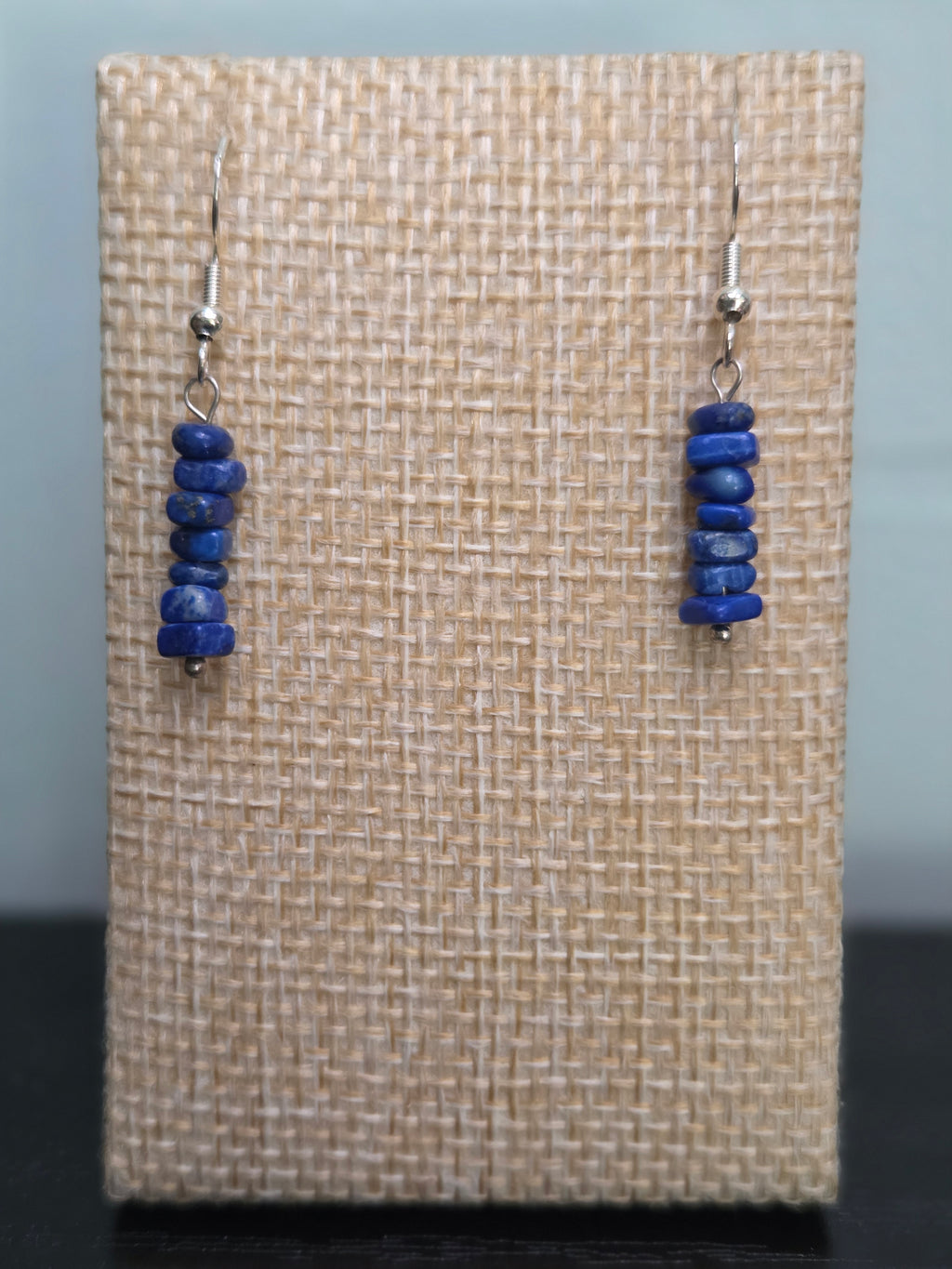 Genuine sodalite chip bead stack earrings in deep blue, close-up on wood grain surface