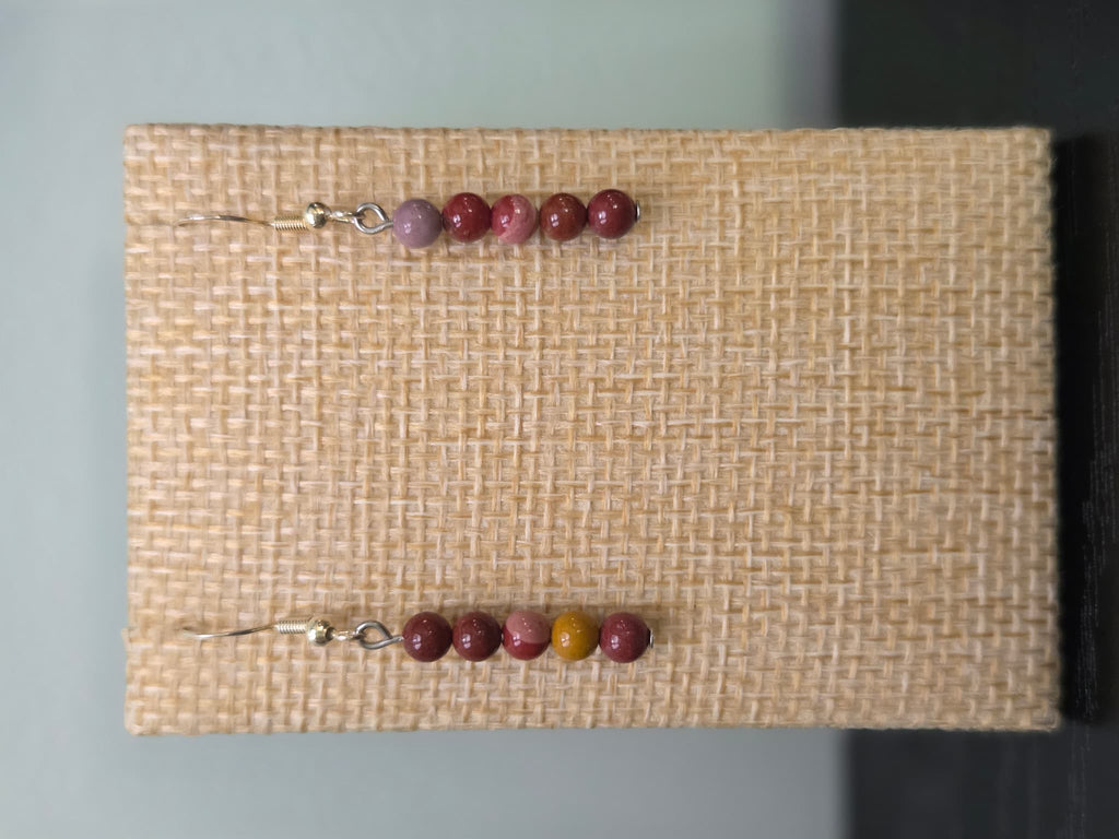 Close-up of genuine mookaite jasper graduated bead earrings in red, pink, and mustard tones