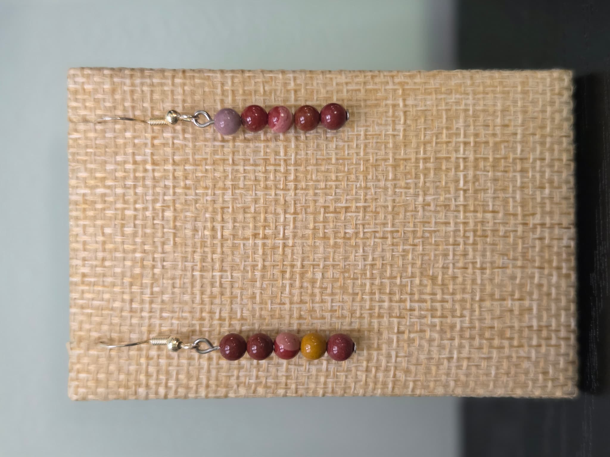 Close-up of genuine mookaite jasper graduated bead earrings in red, pink, and mustard tones