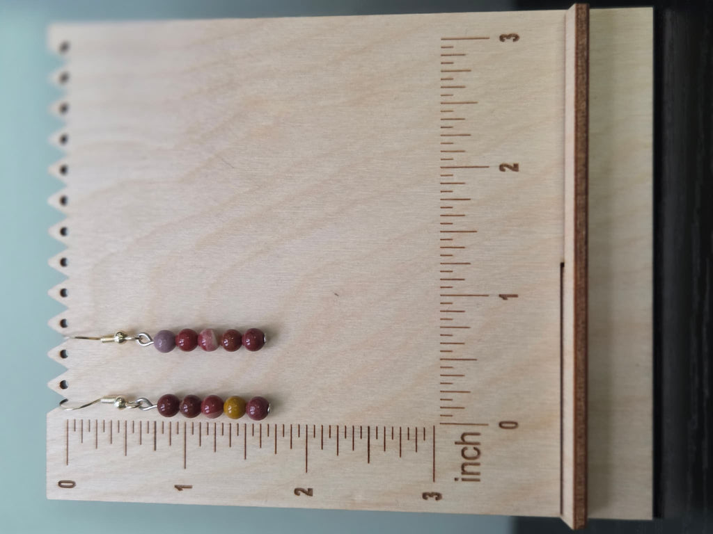 Mookaite jasper graduated drop earrings displayed on a wooden earring stand with ruler showing approximately 1.75 inch length