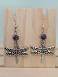 Close-up of silver-tone lattice dragonfly charm earrings with amethyst round bead