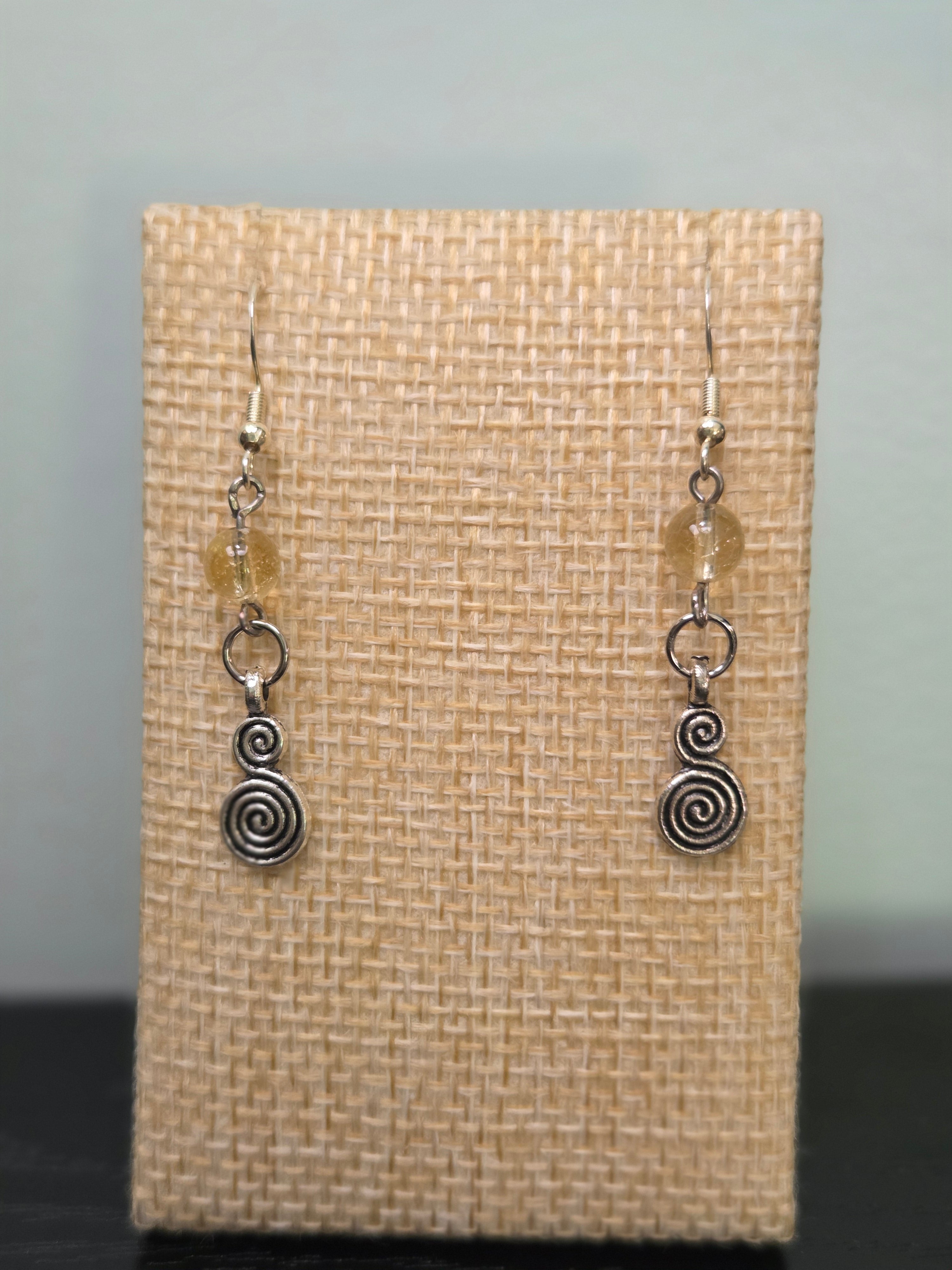 Close-up of silver-tone spiral charm earrings with faceted citrine beads