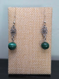 Close-up of silver-tone flower filigree earrings with genuine malachite beads