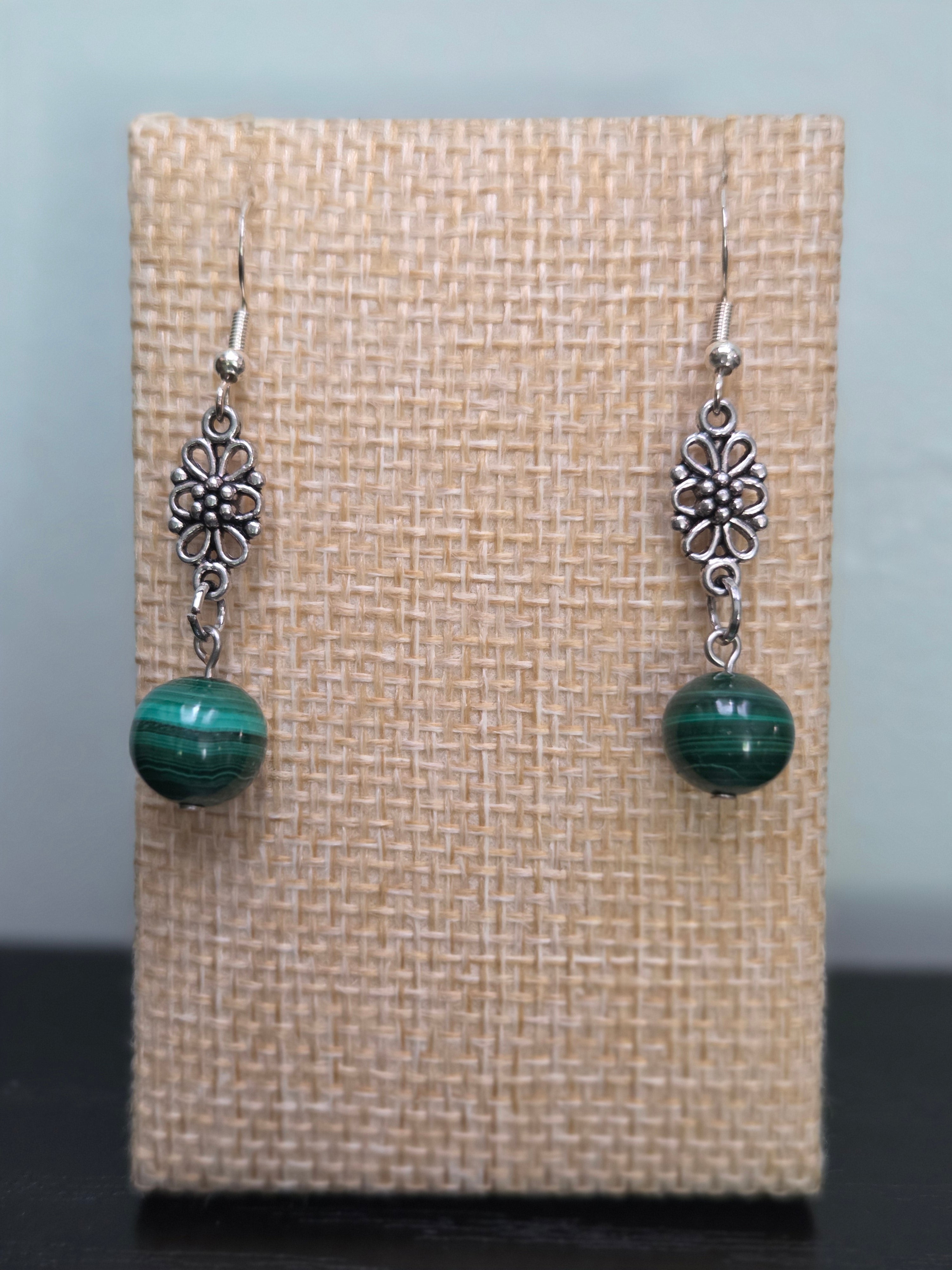 Close-up of silver-tone flower filigree earrings with genuine malachite beads