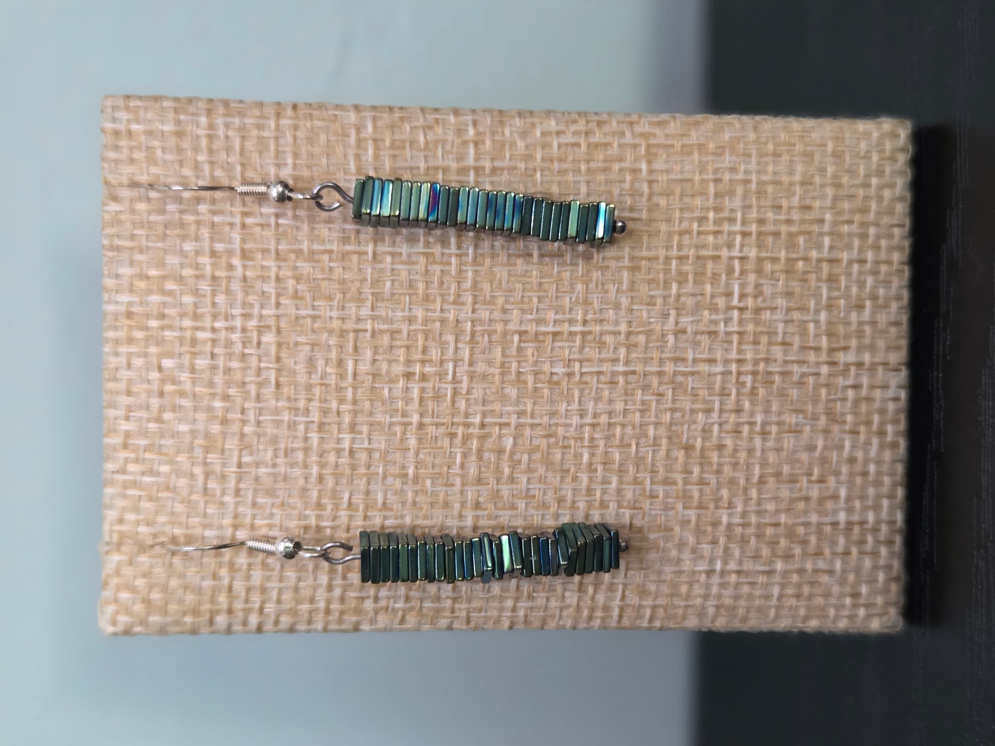 Close-up of Hemalyke square bead stack earrings with iridescent green-gold sheen
