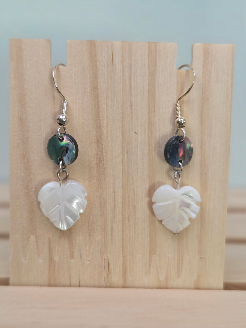 Close-up of abalone shell disc and carved mother-of-pearl heart-shaped leaf earrings
