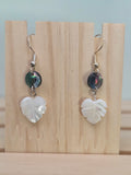 Close-up of abalone shell disc and carved mother-of-pearl heart-shaped leaf earrings