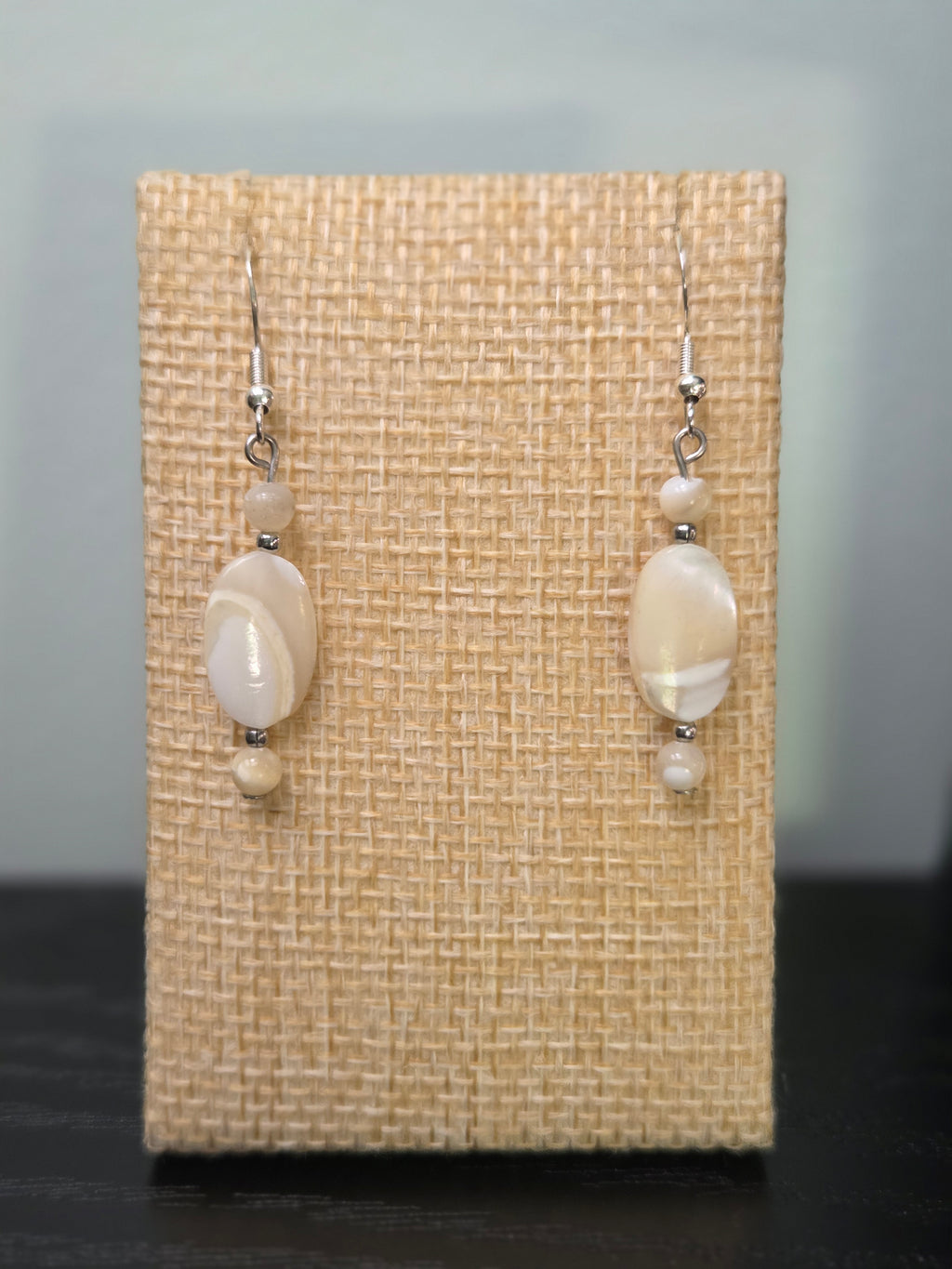Close-up of natural cream and ivory shell bead earrings with silver-tone accents