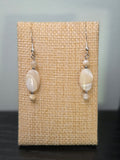 Close-up of natural cream and ivory shell bead earrings with silver-tone accents
