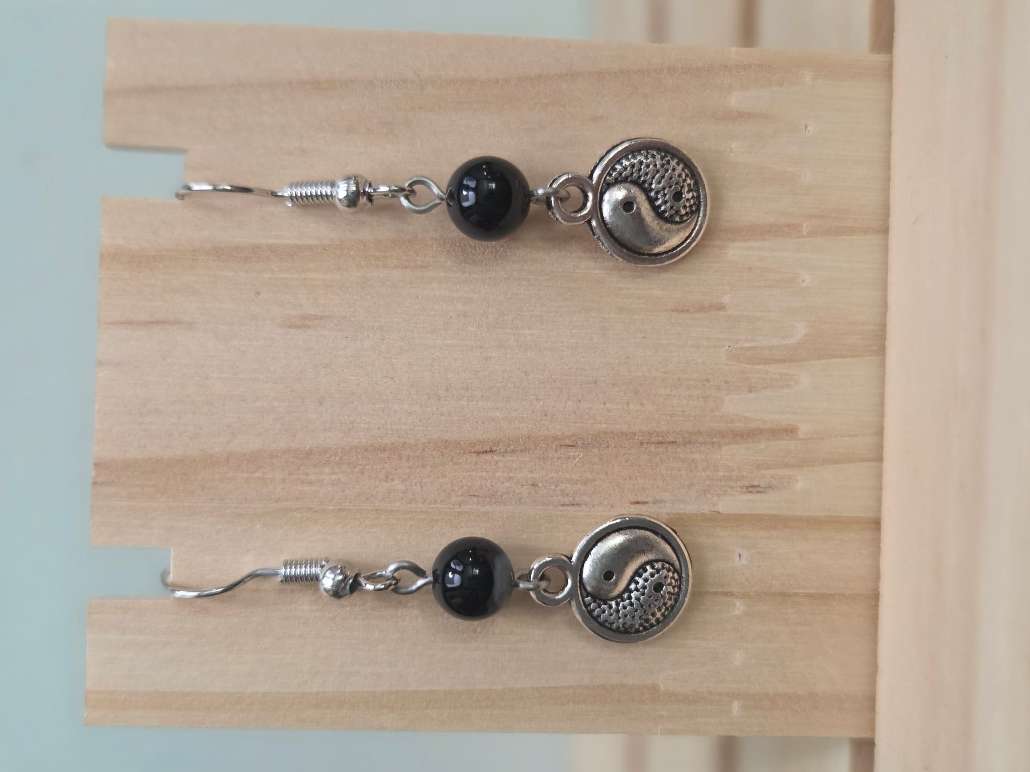 Black onyx beaded earring with silver-tone yin-yang charm on a fish hook ear wire