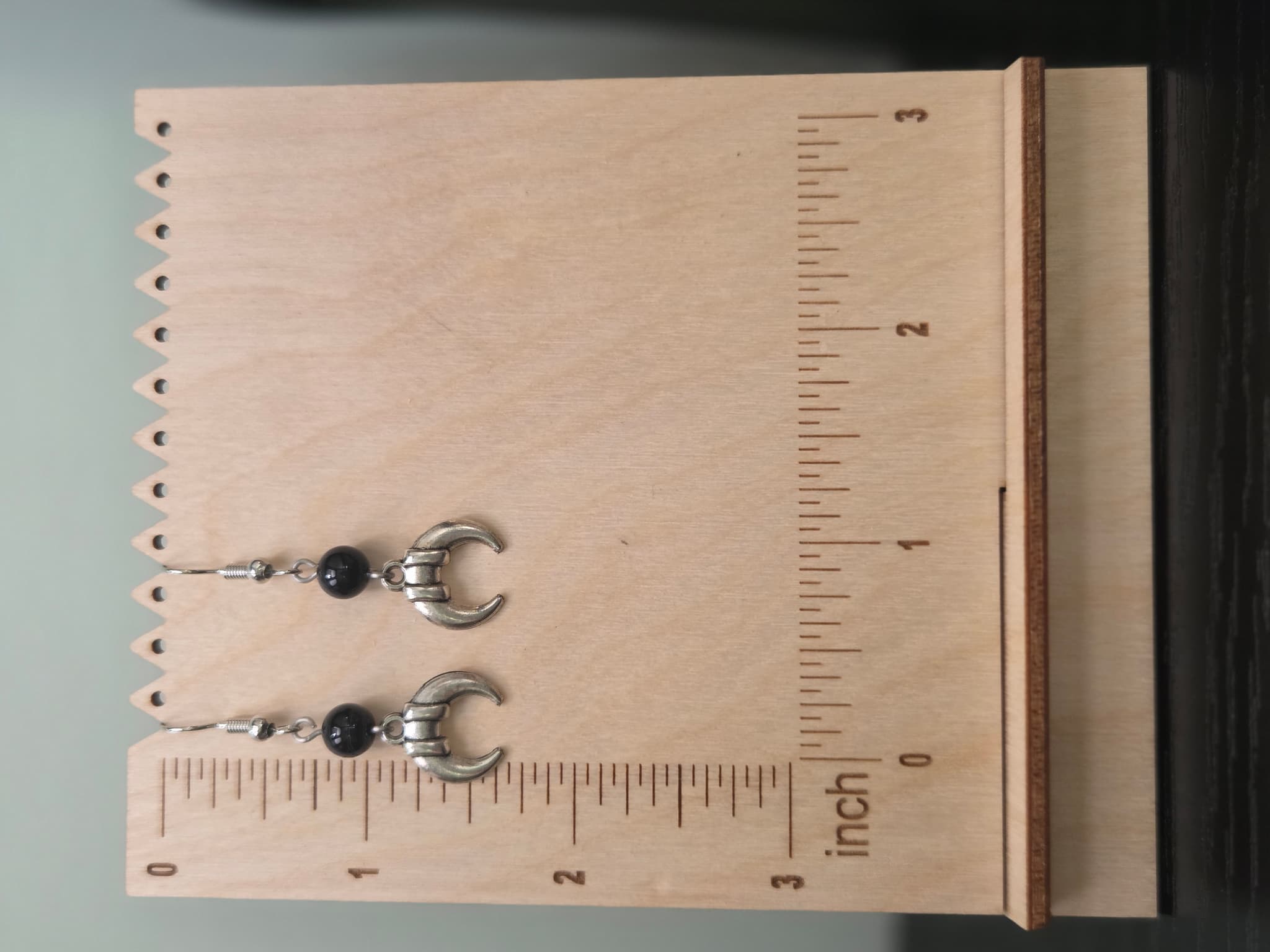 Pair of banded crescent moon onyx earrings shown beside a ruler, approximately 1.75 inches long
