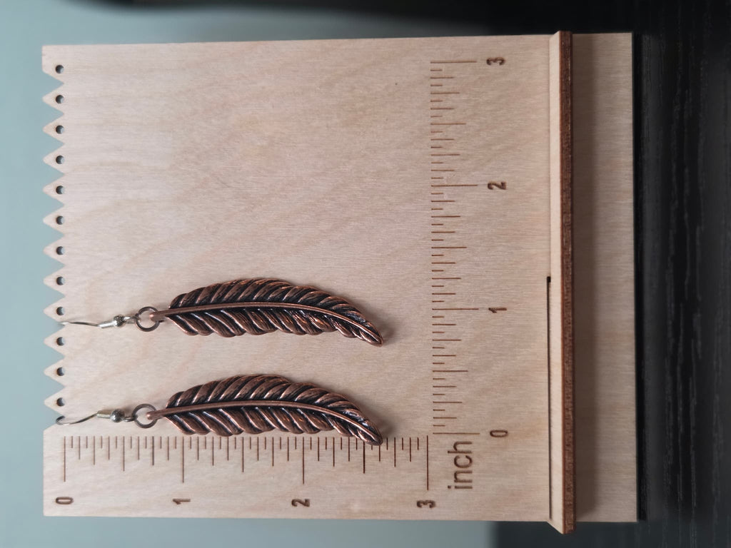 Pair of reclaimed copper-tone feather drop earrings shown against a woven burlap display card