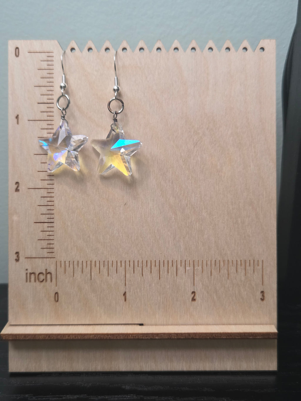 Iridescent AB crystal star drop earrings on wooden display stand with ruler showing approximately 2 inches in length
