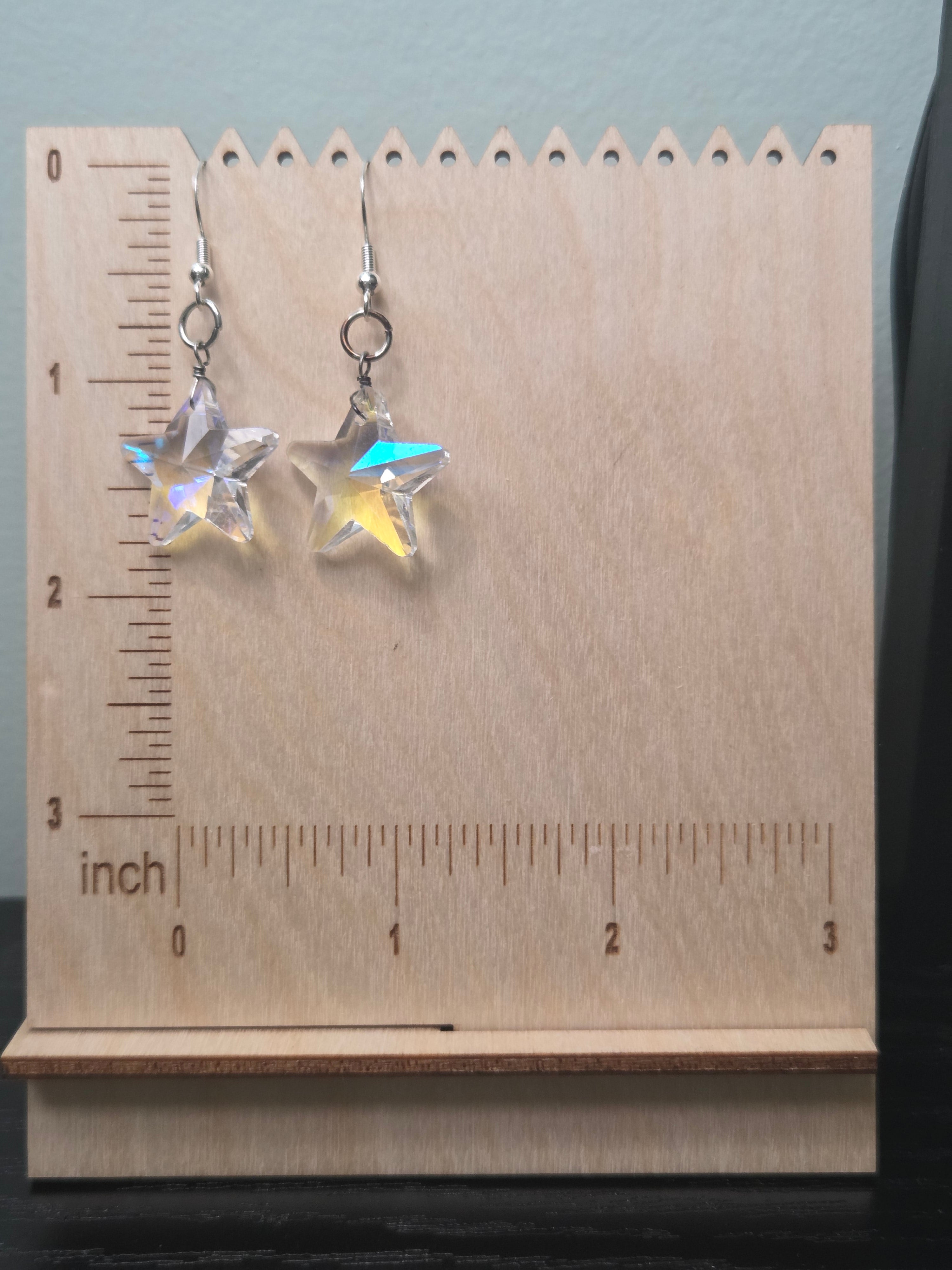 Iridescent AB crystal star drop earrings on wooden display stand with ruler showing approximately 2 inches in length