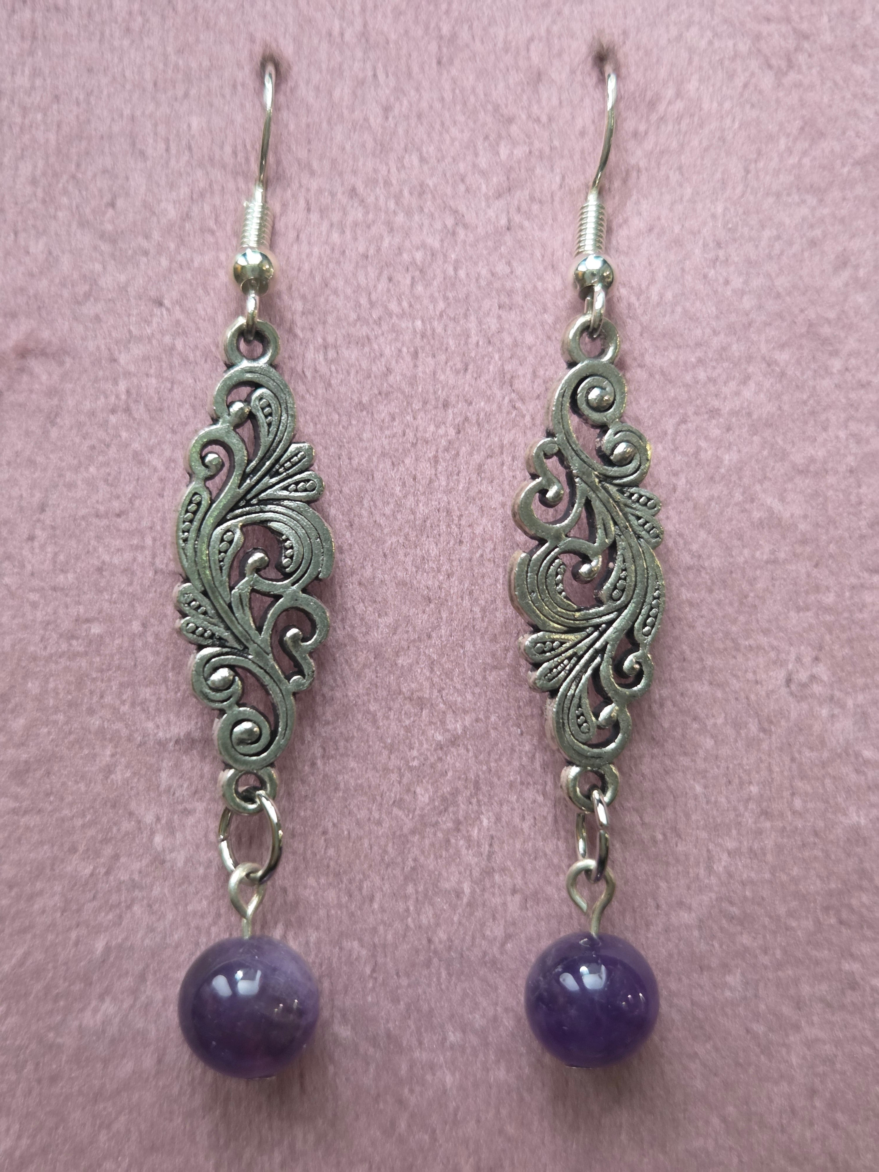 Pair of filigree amethyst drop earrings displayed on wooden ruler board showing approximately 2.25 inch length