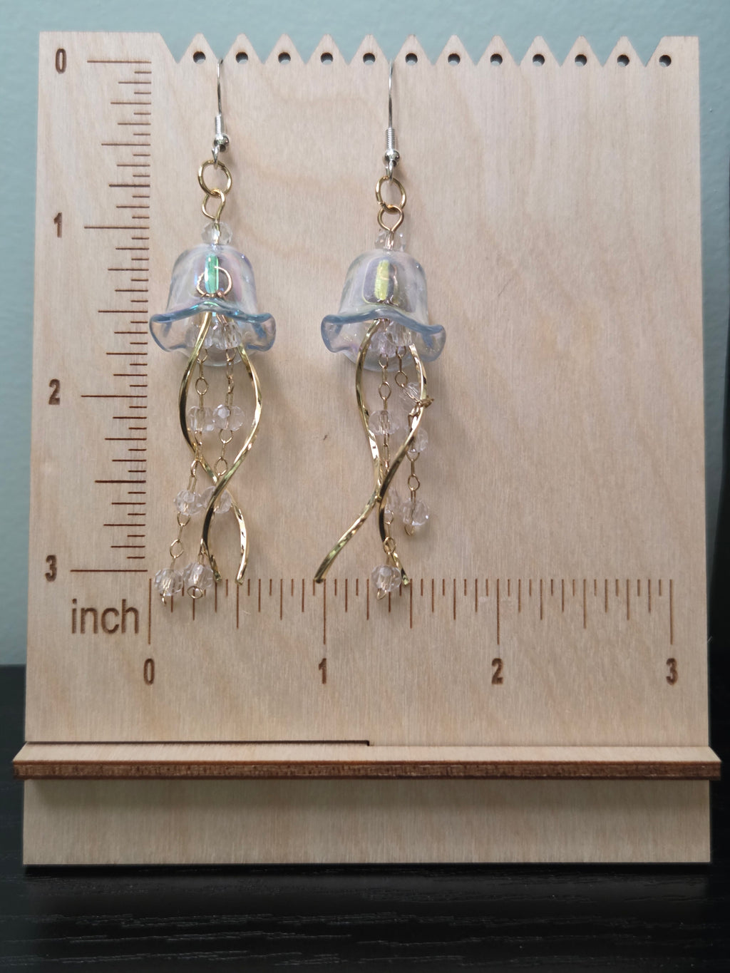 Iridescent jellyfish dangle earrings on wooden ruler board, ~2.5" length, acrylic bell caps, gold-tone twisted wire tentacles, crystal beads, silver fishhook ear wires