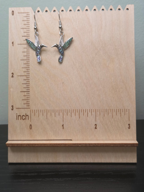 Abalone-style acrylic inlay hummingbird dangle earrings, silver-tone setting, shown on wood display