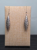Pair of silver-tone marquise drop earrings with an etched leaf and floral design, shown on a wooden ruler stand measuring approximately 1.75 inches