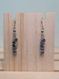 Pair of faceted hematite stack drop earrings shown on a wooden ruler stand measuring approximately 1.5 inches