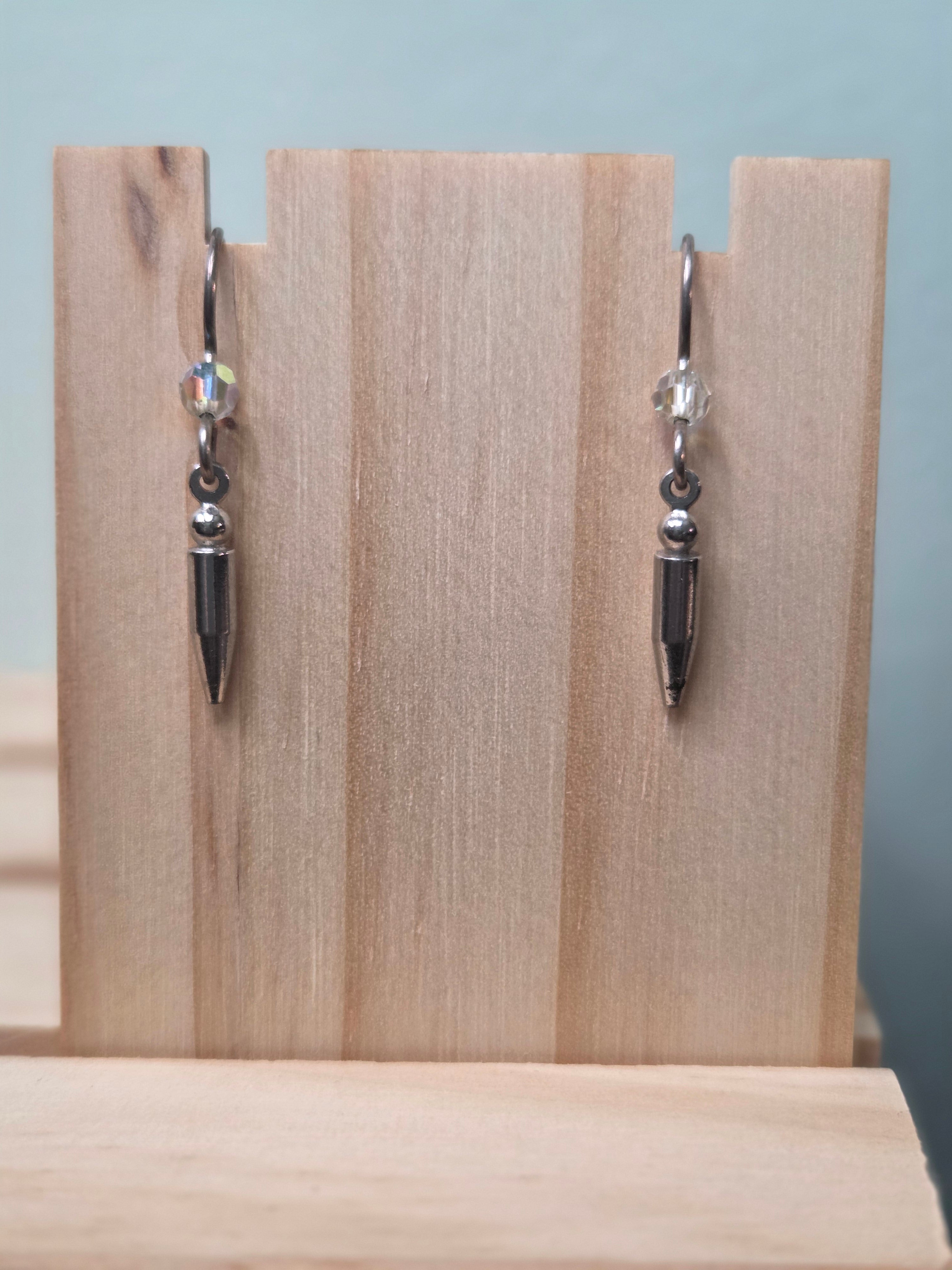 Gunmetal spike charm dangle earrings with faceted crystal accent, shown on wood display