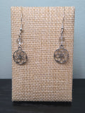 Small Seed of Life sacred geometry charm earrings with clear quartz bead, silver-tone, shown on wood display