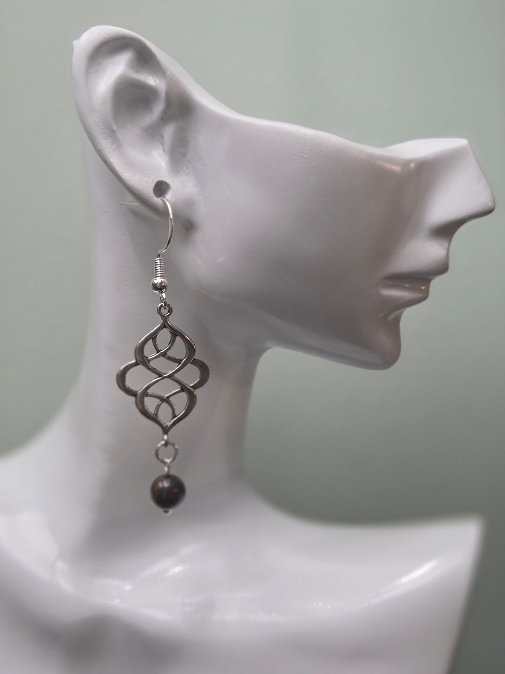 Tiger's eye swirl knot dangle earrings against ruler showing approximately 2 inch length