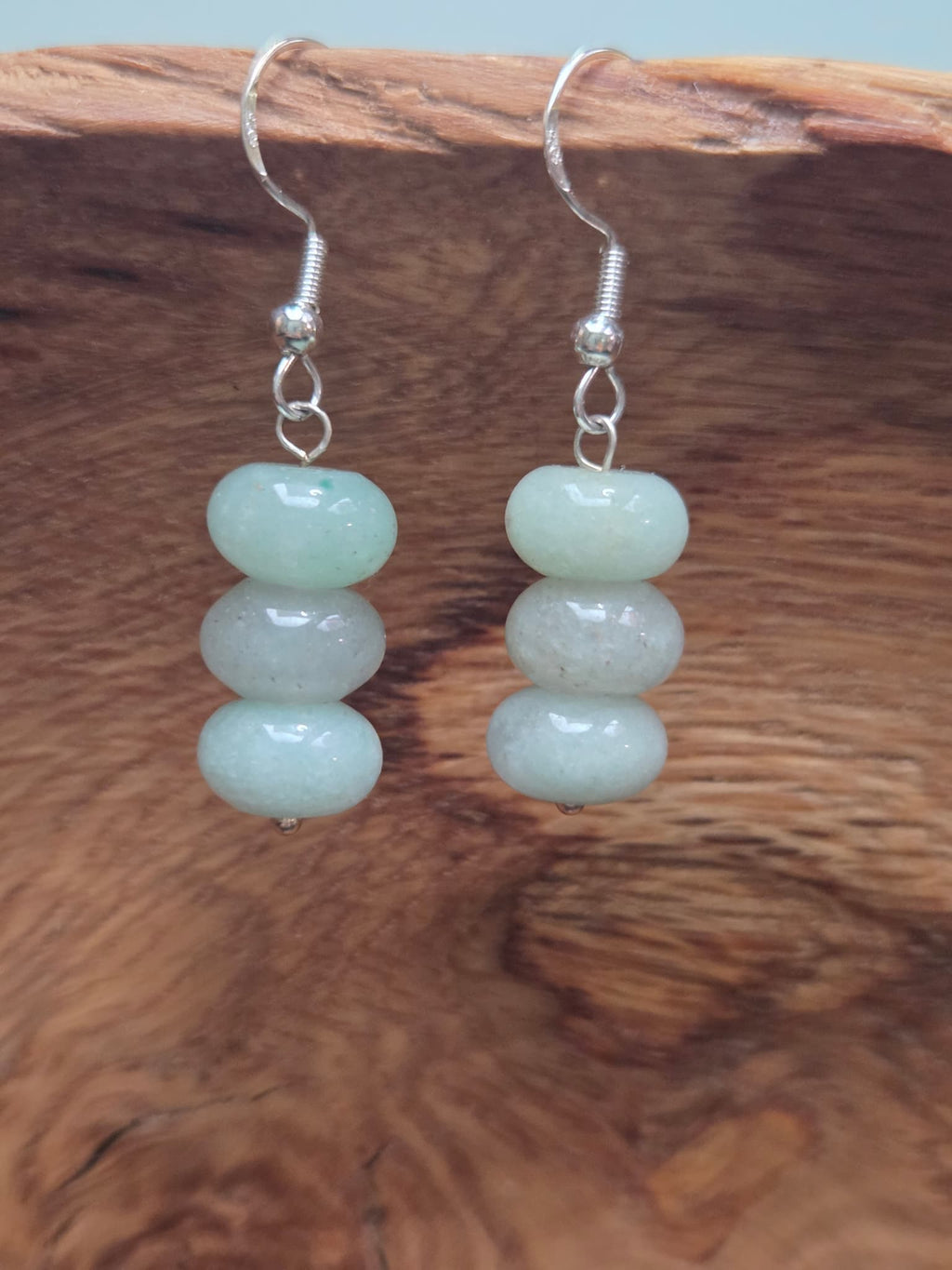 Aventurine triple stack drop earrings with three genuine aventurine rondelle beads, shown on a wood grain surface