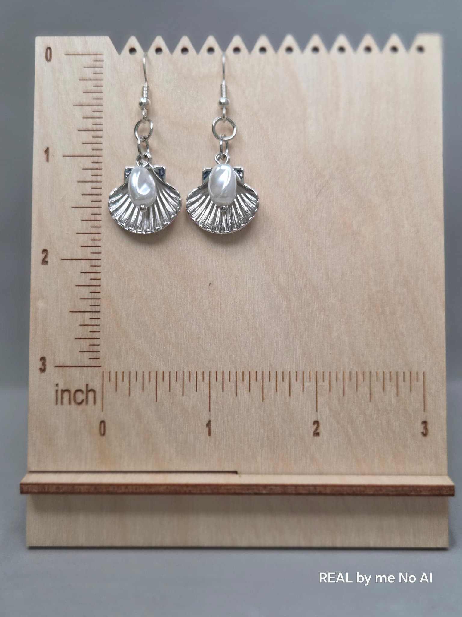 Close-up of the silver-tone shell charm and shell pearl detail on dangle earrings