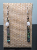 Freshwater pearl and abalone-style resin bar drop earrings with gold-tone findings, shown on a woven fabric background