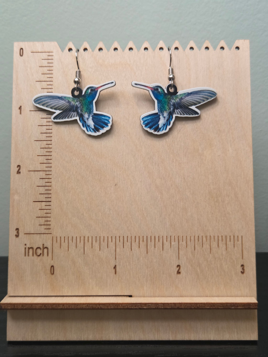 Realistic printed acrylic hummingbird dangle earrings against ruler showing approximately 1 inch length