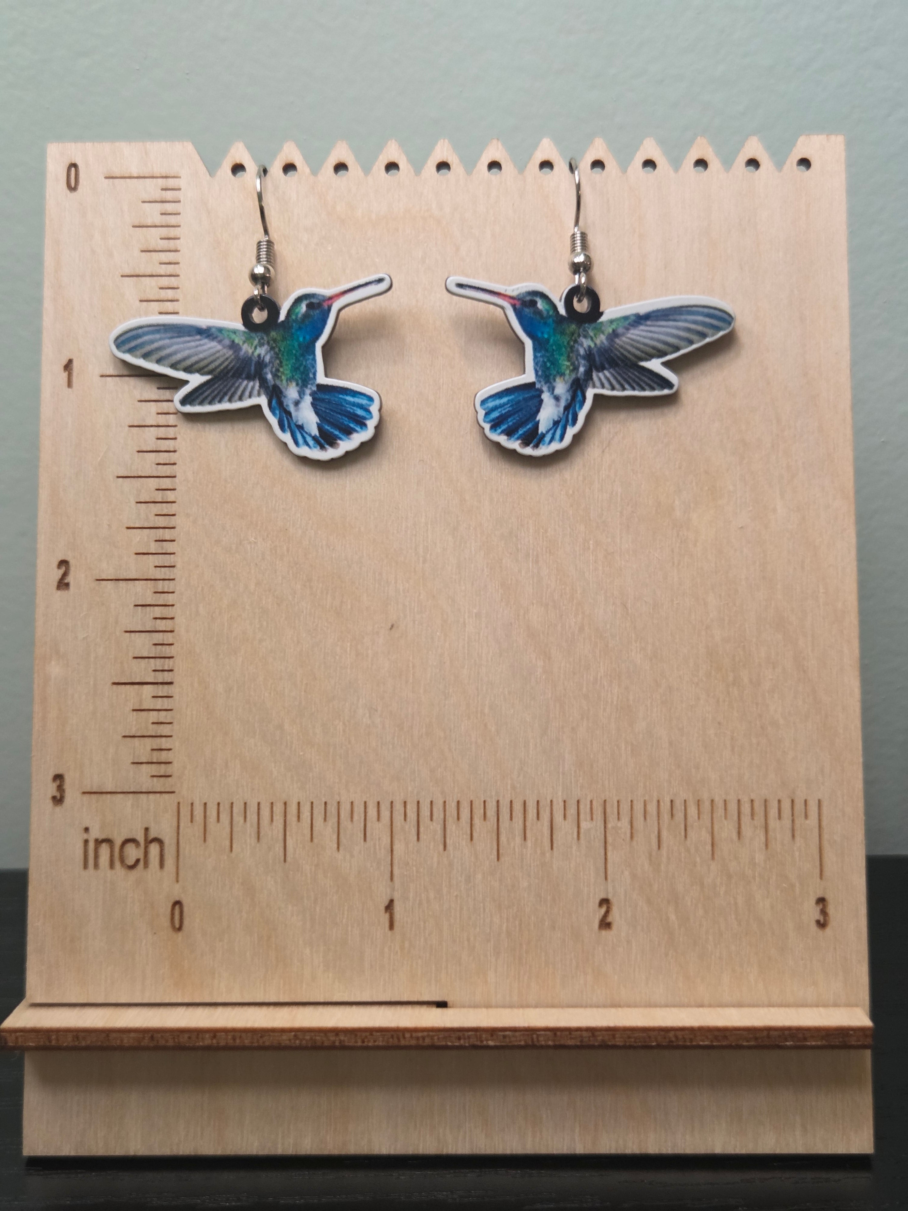 Realistic printed acrylic hummingbird dangle earrings against ruler showing approximately 1 inch length
