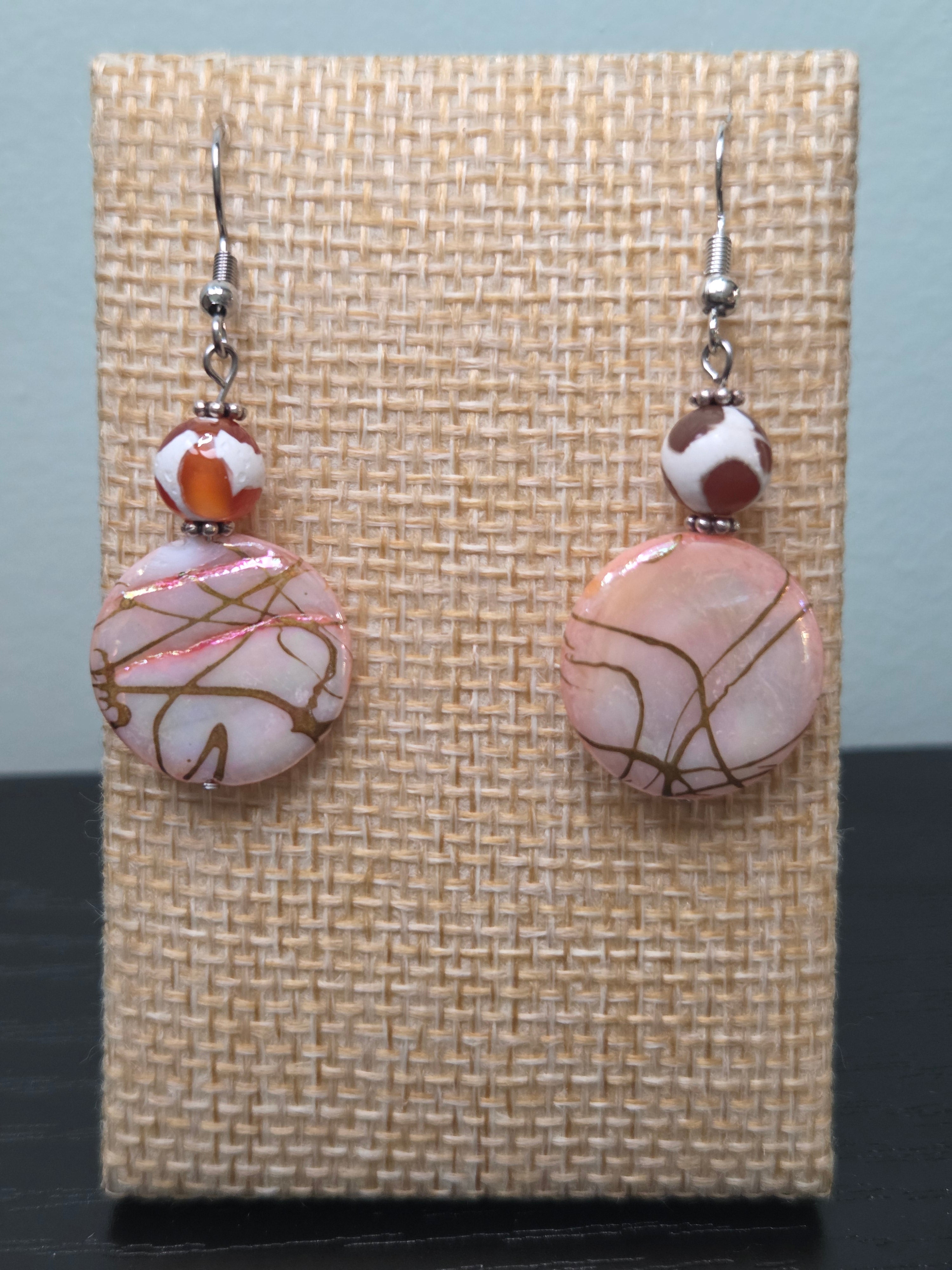 Crackle glass disc drop earrings with mottled glass accent bead, displayed on a wooden earring stand with ruler showing approximately 2 inch length