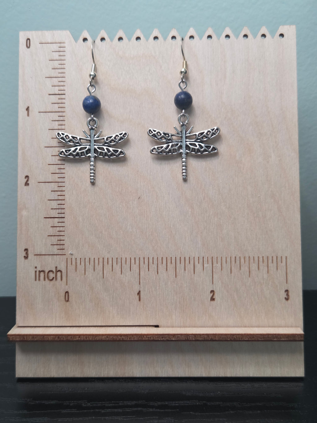 Close-up of dragonfly charm and genuine sodalite bead earrings on wood grain surface
