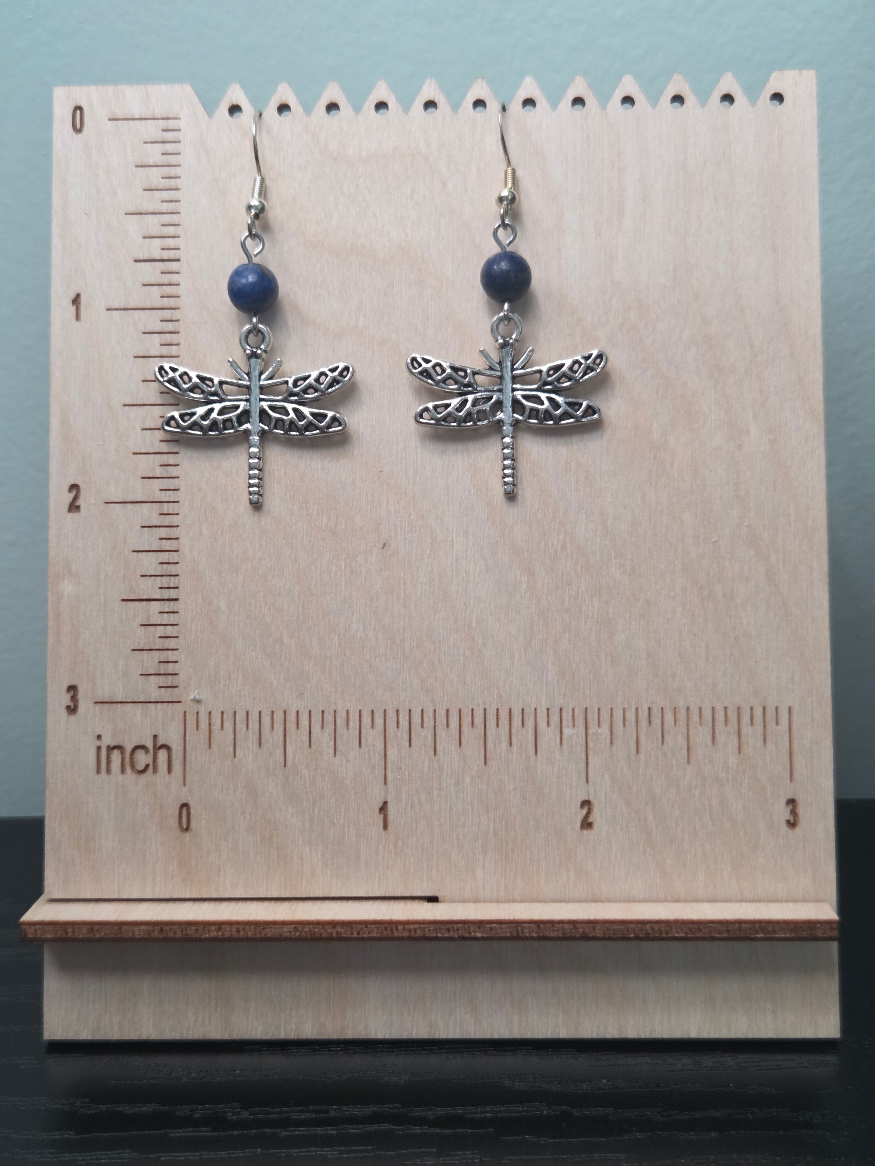 Close-up of dragonfly charm and genuine sodalite bead earrings on wood grain surface