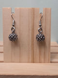 Pair of small silver-tone woven texture ball drop earrings, shown on a wooden ruler stand measuring approximately 1 inch