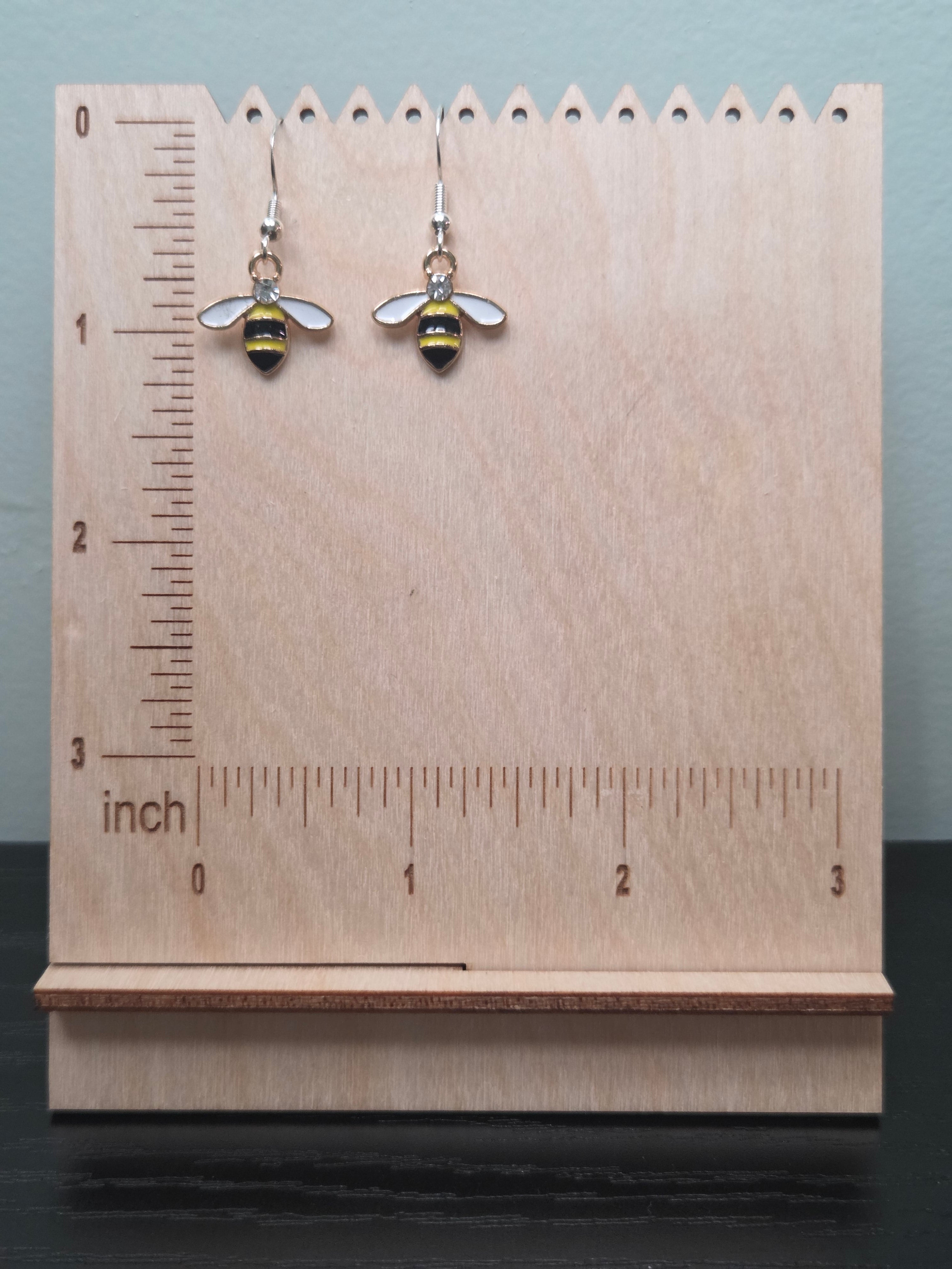 Gold-tone enamel bee dangle earrings against ruler showing approximately 1.3 inch length