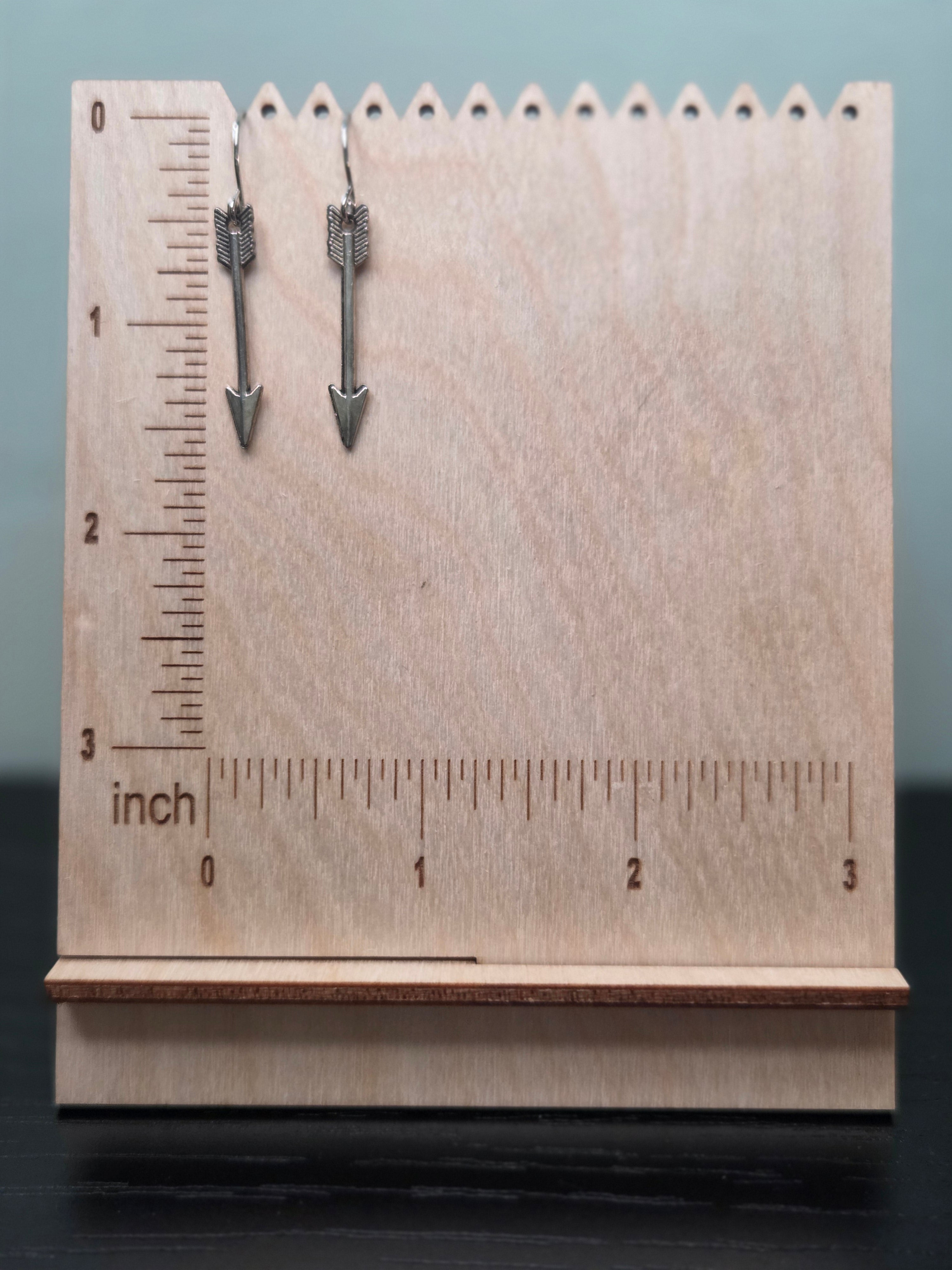 Gunmetal-tone arrow charm dangle earrings against ruler showing approximately 1.7 inch length