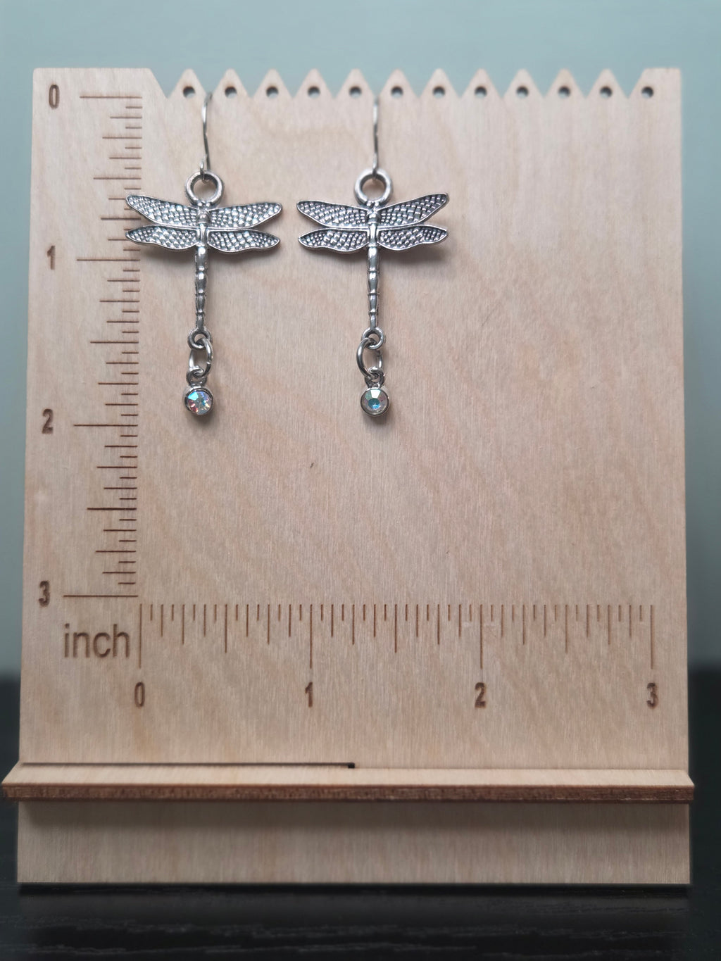 Silver-tone dragonfly dangle earrings against ruler showing approximately 2 inch length